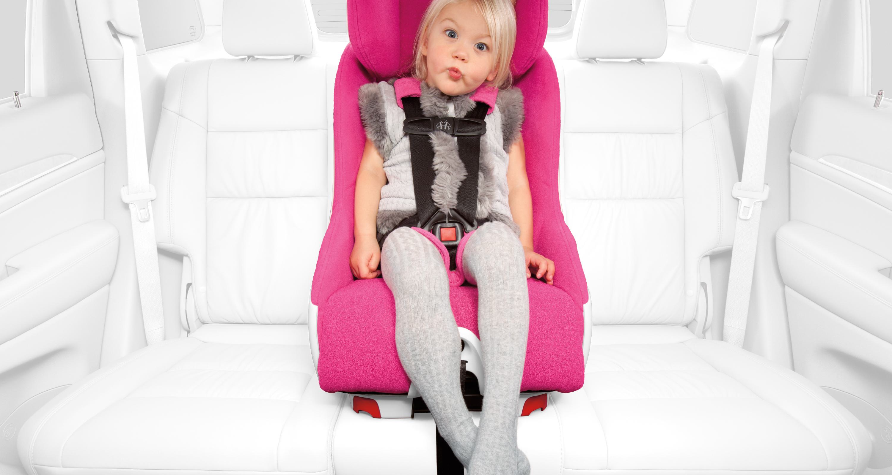 A girl sitting in a Foonf child seat in a car with a stylized white interior