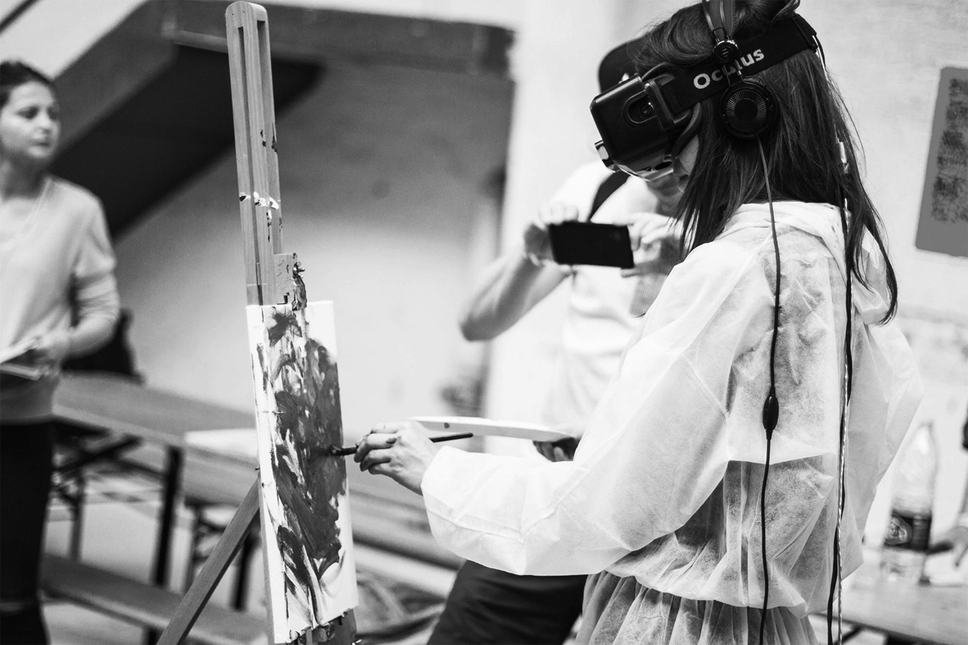A woman painting while wearing a virtual reality goggles.