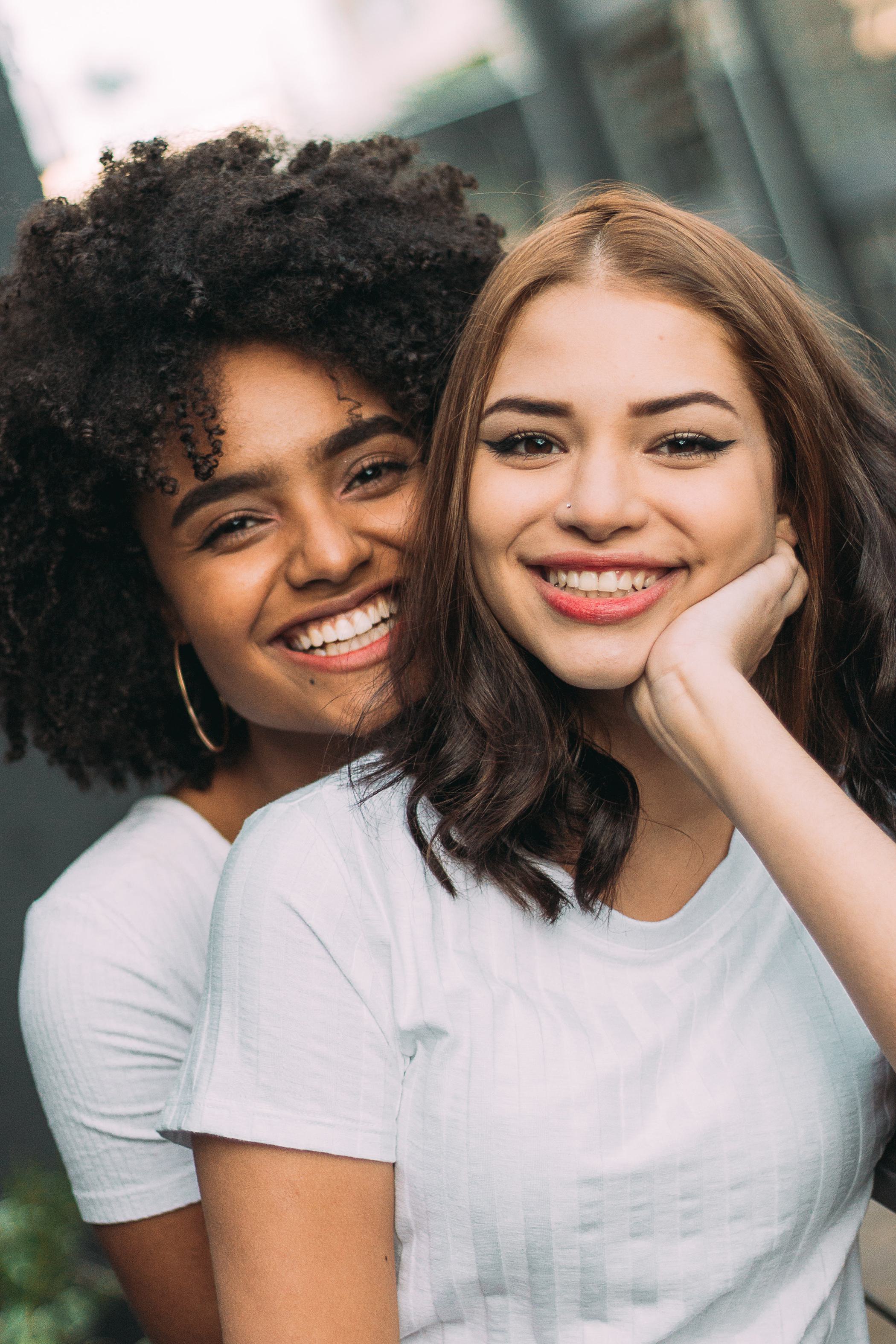Two diverse young women standing close to each other and smiling